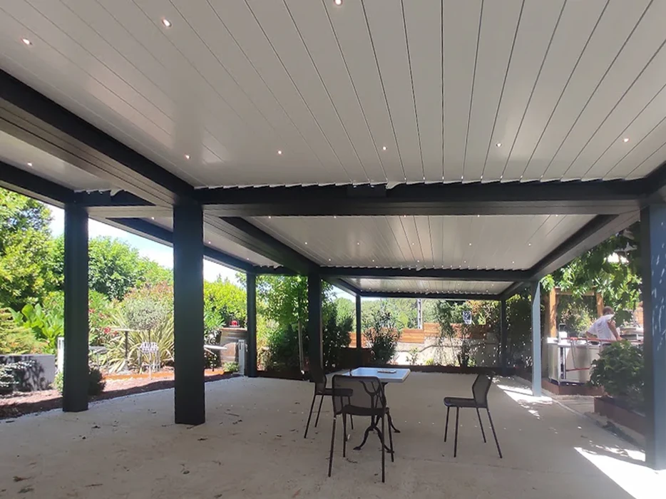 Terrasse couverte extérieure avec pergola bioclimatique à lames orientables blanches et structure métallique anthracite