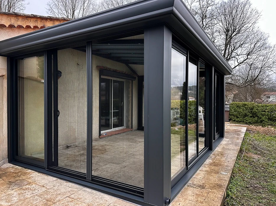 Terrasse extérieure surélevée d'une maison moderne avec pergola bioclimatique à lames orientables en aluminium gris anthracite