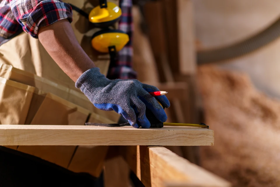 Homme en chemise noire mesurant un plan de travail en bois avec un m&egrave;tre ruban jaune dans une cuisine moderne