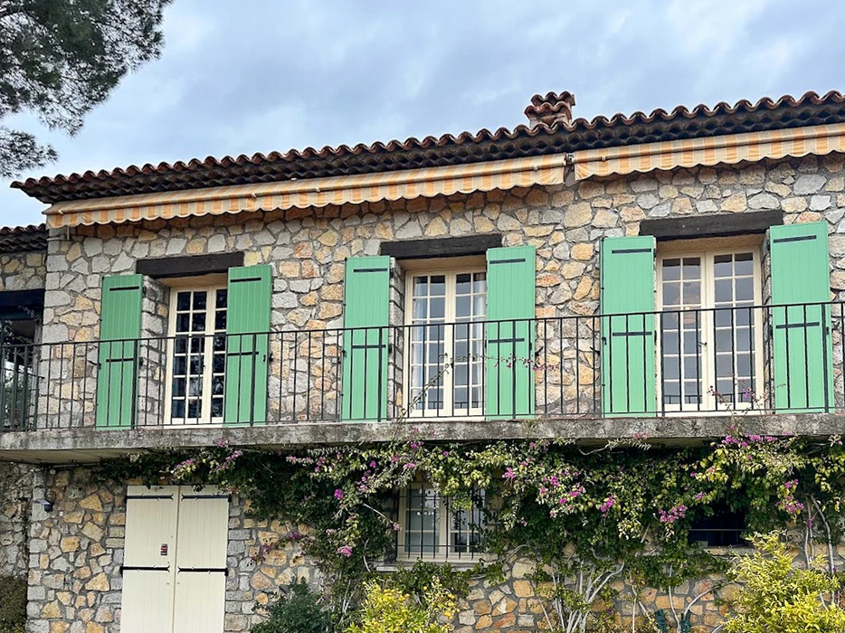 Intérieur moderne avec véranda vitrée, canapé en bois et coussins blancs, plantes vertes en pots