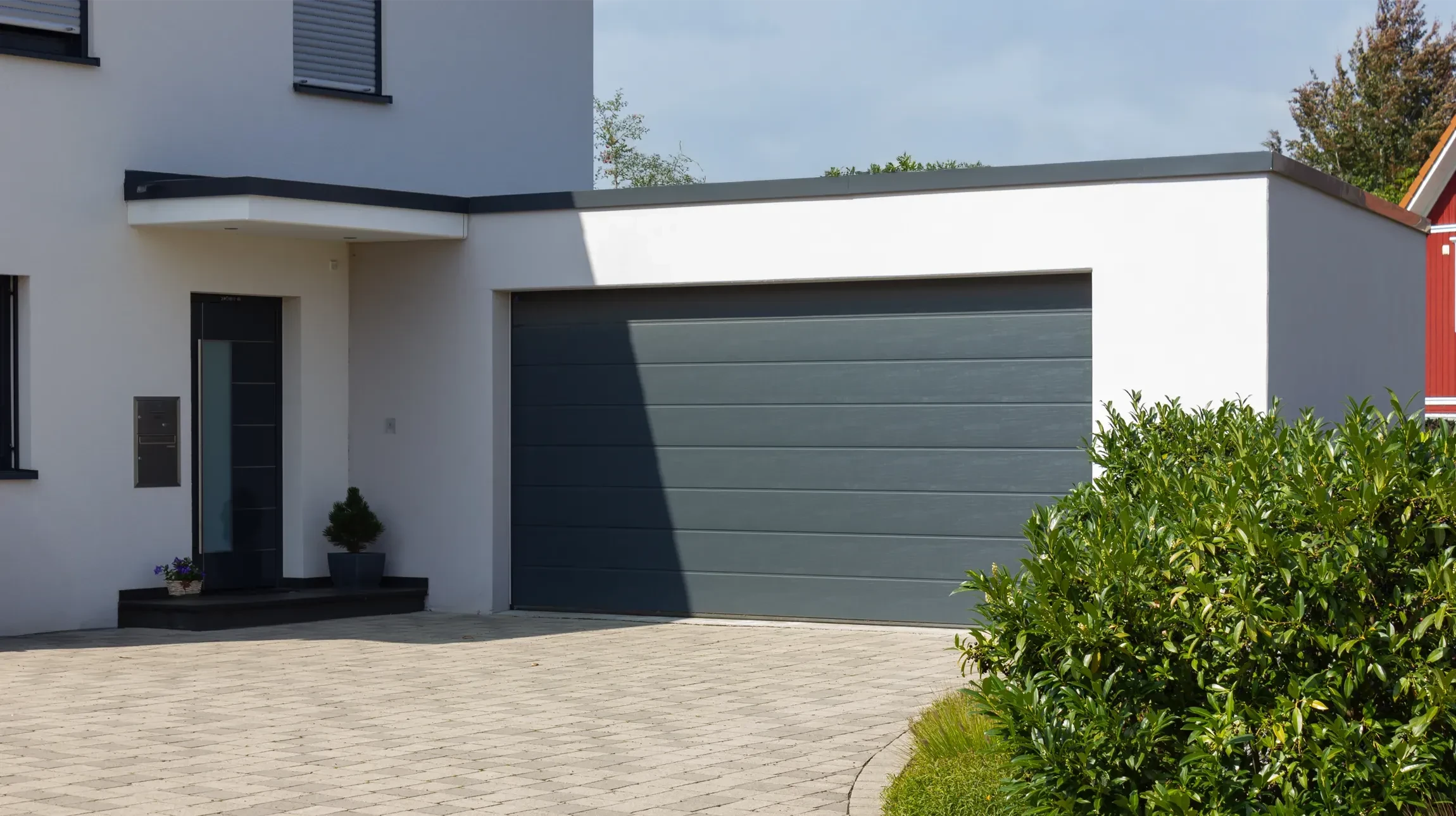 Façade de maison contemporaine avec garage intégré et aménagement paysager